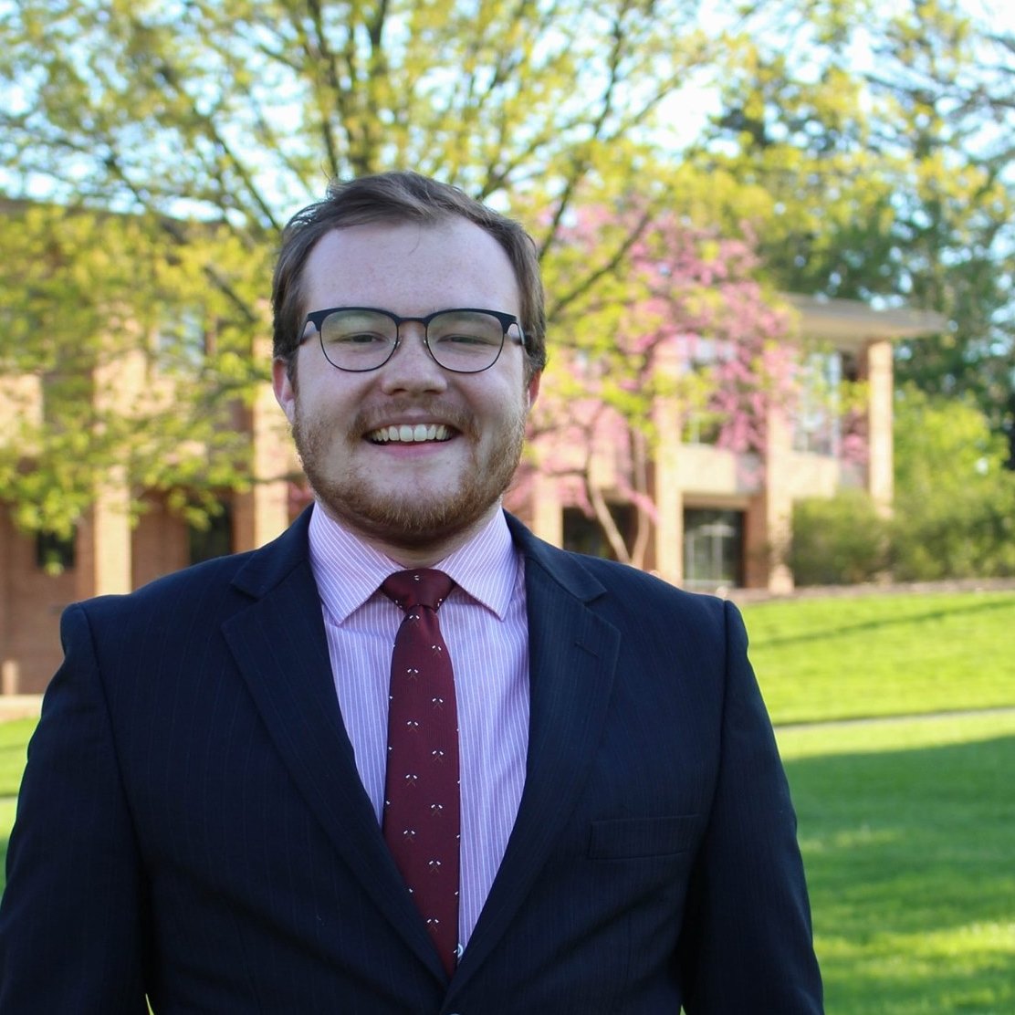 A portrait of Garrett in a suit and tie at his Alma Mater, Calvin University